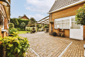 Neat paved patio with sitting area and small garden near wooden fence