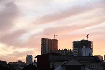 Fototapeta na wymiar Tower cranes near unfinished buildings in city