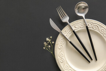 Plate, cutlery and gypsophila flowers on black background