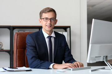 Young bank manager working with computer at table in office