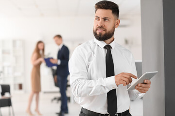 Fototapeta premium Confident young businessman using digital tablet in modern office environment business technology and communication, man