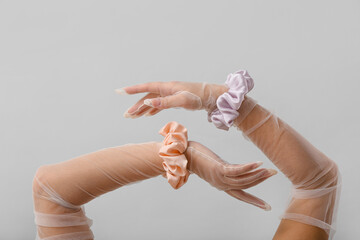 Female hands in gloves with silk scrunchies on light background