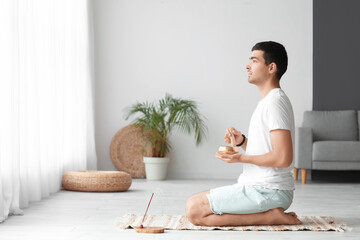 Young man with Tibetan singing bowl at home