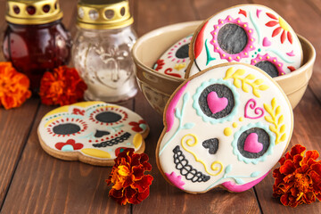 Bowl with skull shaped cookies and flowers on wooden background, closeup. El Dia de Muertos