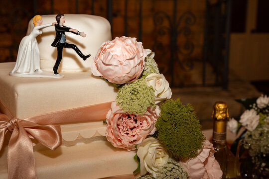 dettaglio decorazione floreale torta nuziale prima del taglio con decorazione di nastrini e statuette in gesso e resina durante un matrimonio in esterna