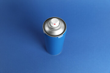 Can of spray paint on blue background, above view