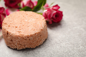 Solid shampoo bar and roses on light grey table, closeup. Space for text