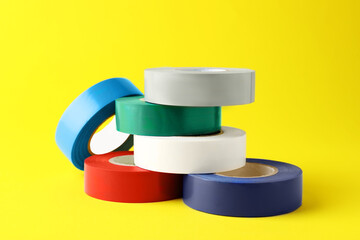 Colorful insulating tapes on yellow background. Electrician's supplies