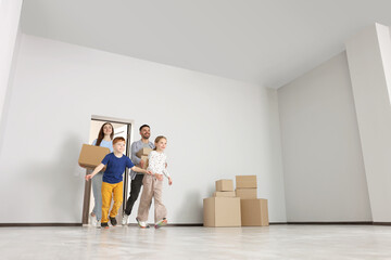 Happy family with moving boxes entering in new apartment, low angle view. Settling into home