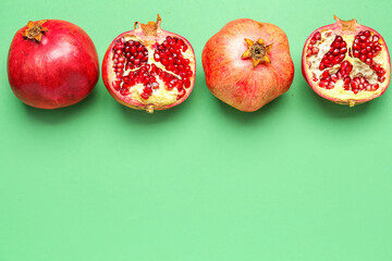 Whole and cut pomegranates on green background