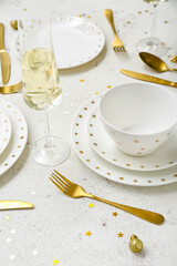 Beautiful table setting with golden Christmas balls on white background