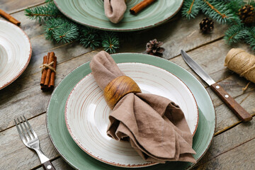 Beautiful table setting with Christmas branches, fir cones and cinnamon on wooden background,...