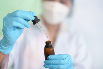 Modern Medical Research Laboratory: Work Chemist pipetting drop fluid of a bottle in the products...
