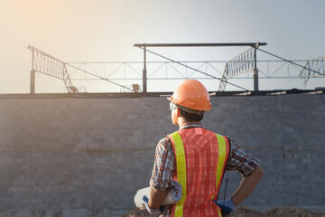 worker with  safety vest and  safety helmet hold the blue print working at site line.