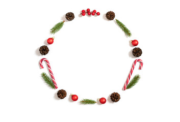 Naklejka premium Christmas round frame with fir branches, cones, baubles and lollipops isolated on a white background. New Year wreath. Copy space, top view, flat lay.