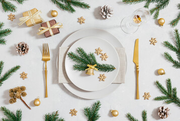 Christmas table setting with golden cutlery, festive decor and fir branches. New Year party. Preparing for Christmas dinner. Top view, flat lay.