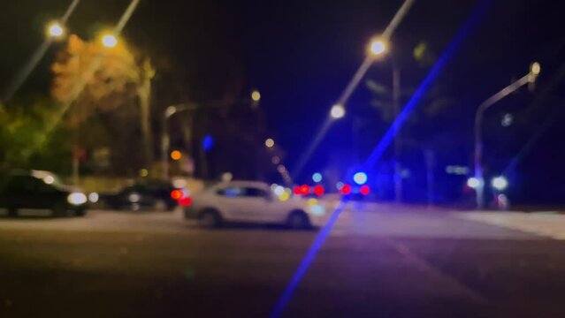 Police or ambulance car flashing lights, traffic accident, walking people, city street in soft focus