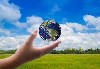Hand holding globe with fields and bright sky behind. Concept concept, protect environment. save the world from pollution clean or renewable energy