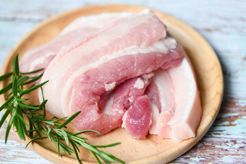 fresh raw streaky pork meat for cooking food, pork skin pig skin, pork on wooden plate with rosemary