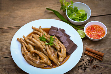 Cooking chicken feet foot stew on white with herbs and spices ingredients with chilli lemon vegetable on wooden background, Asian chinese food menu stew, Thai food, chicken feet soup stewed