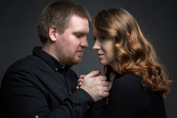 Man and woman tenderly hold hands. Support, love and relationship problems. Dark gray background. Close-up.