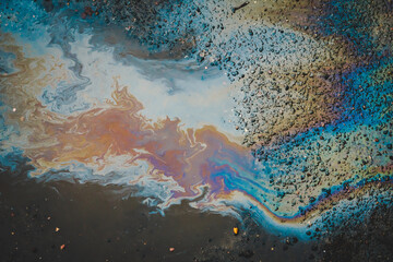 Fototapeta na wymiar A puddle of spilled oil product on the road. Environmental pollution concept