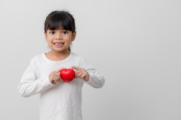 Portrait of Asian little girl child holding red heart sign on white background