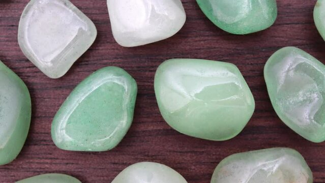 Green Aventurine rare jewel on brown varnished wood texture. Moving right seamless loop backdrop.