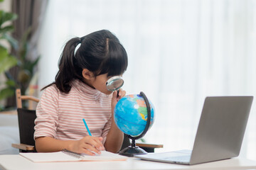 Asian little girl is learning the globe model, concept of save the world and learn through play activity for kid education at home.
