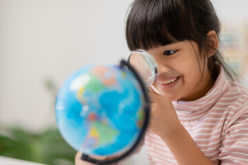Asian little girl is learning the globe model, concept of save the world and learn through play activity for kid education at home.