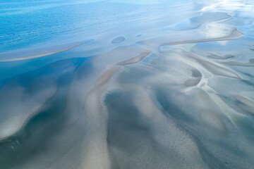 Aerial view of sandbar patterns in shallow blue water.