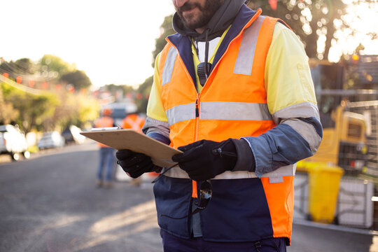 Close up shot of a man road worker with beard wearing high-vis workwear holding his notes