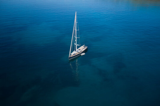 White sailing yacht on transparent water top view. Modern expensive sailing yacht on transparent turquoise water aerial view.