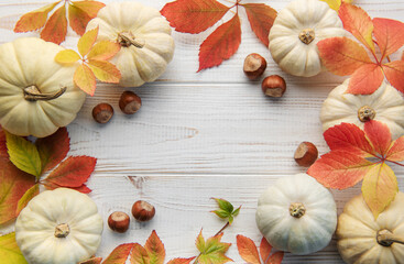 Autumn leaves and pumpkins over old wooden background
