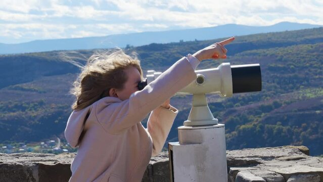 a little girl looks through binoculars on an observation deck in a tourist spot