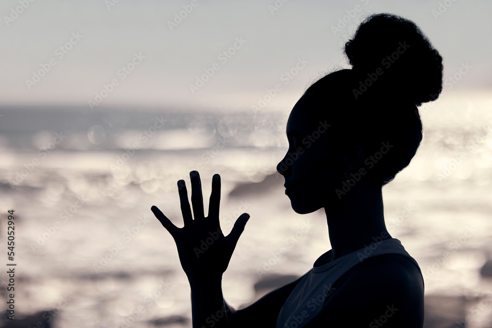 Wall mural Meditation, wellness and silhouette of woman at a beach doing yoga, exercise and workout. Fitness, mindfulness and shadow of head and hands of female by ocean to meditate, calm and relax in training