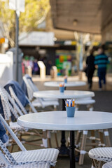 A row of outdoor tables and chairs of a cafe