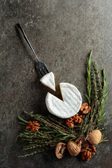 Brie cheese with walnuts, thyme, and rosemary on an old stone table.