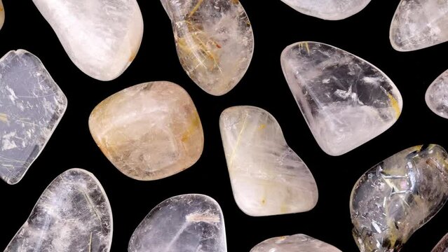 Rutilated quartz rare jewel stones texture on black background. Moving right seamless loop backdrop.