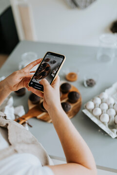 Woman taking picture of freshly baked cupcakes