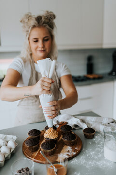 Woman putting icing on cupcakes