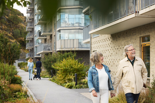 Senior and young couple with baby stroller walking in residential area
