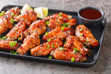 Asian fast food baked chicken wings in hoisin sauce with sesame seeds, served with green onion and...