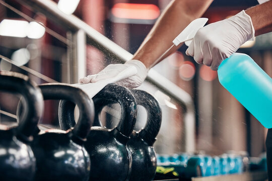 Kettlebell, Cleaning Service And Hands Cleaning At A Gym With Liquid Soap In Spray Bottle With Cloth In Gloves. Janitor Or Cleaner Wipes Dirty Bacteria On Dusty Weights Or Fitness Training Equipment