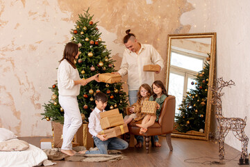 Family - father, mother and three children, happy together at home celebrating Christmas at a decorated Christmas tree