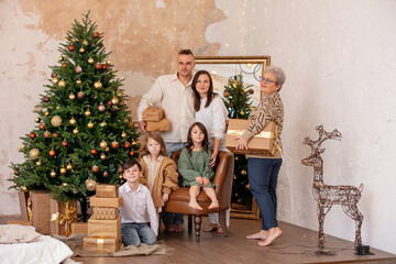 Family - father, mother, grandmother and three children, happy together at home celebrating Christmas at a decorated Christmas tree