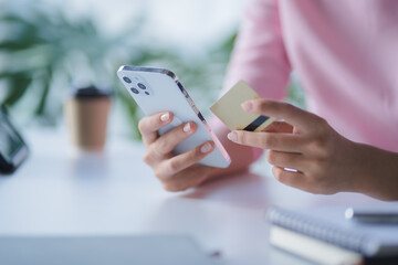Closeup asian woman holding gold credit card and smartphone, sitting at home, happy satisfied young female customer shopping online, purchasing, making secure online payment.