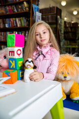 Cute little girl chooses a book in the library