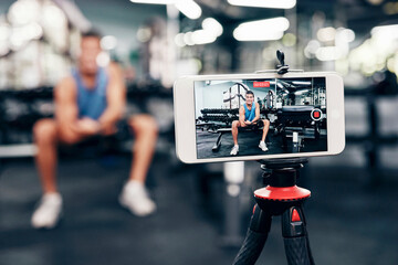 Gym, social media and fitness influencer with phone live streaming workout for interactive multimedia broadcast. Vlog, man filming arm exercise and training coach video recording online blog tutorial - obrazy, fototapety, plakaty