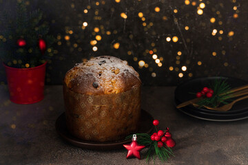 Traditional dessert for Christmas, Panettoni , Italian cake with raisins and candied fruits on concrete table with Christmas tree and golden bokeh decoration
